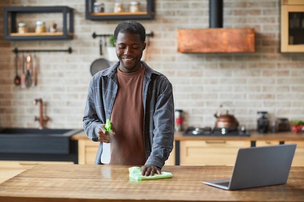 Portrait of smiling AfricanAmerican man enjoying spring cleaning in modern home interior copy space