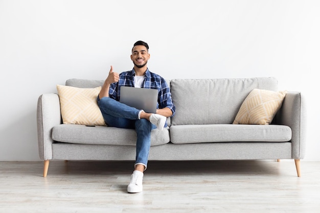 Portrait of smiling arab man using laptop showing thumbs up