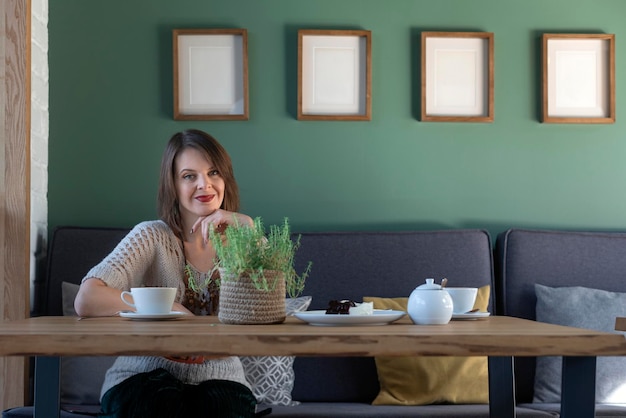 Portrait of smiling attractive woman in cafe looking at camera Lonely woman sits in cafe