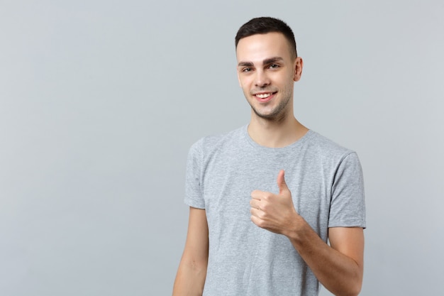 Portrait of smiling attractive young man in casual clothes standing and showing thumb up 