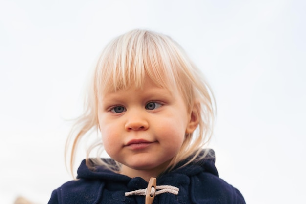 Portrait of smiling baby boy sitting on sand on beach in autumn time