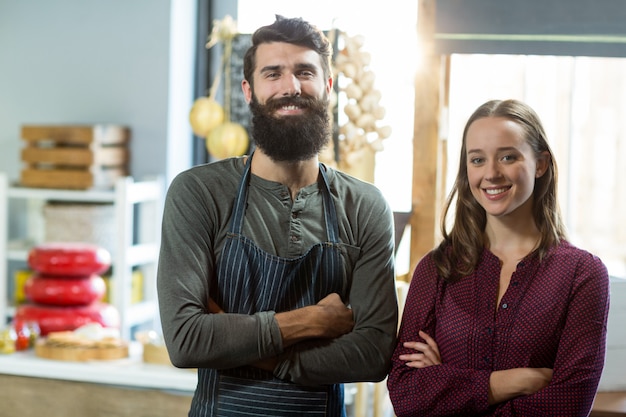 Portrait of smiling bakery staff standing with arms crossed