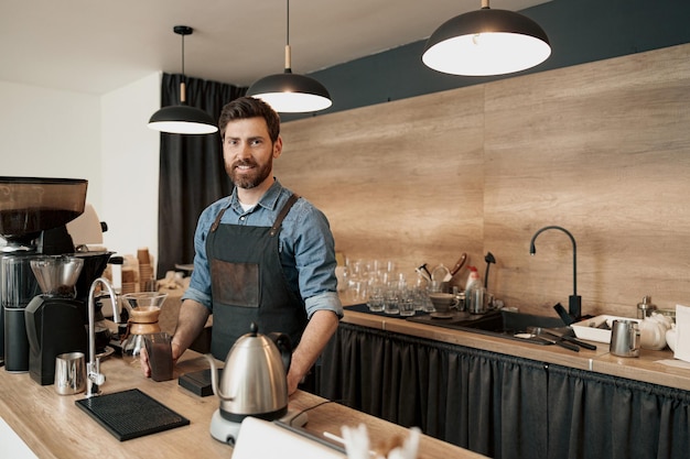 Portrait of smiling barista with stylish beard while behind a counter in the coffeeshop