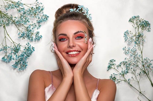 Portrait of a smiling beautiful sweet girl on a white background with white and blue flowers