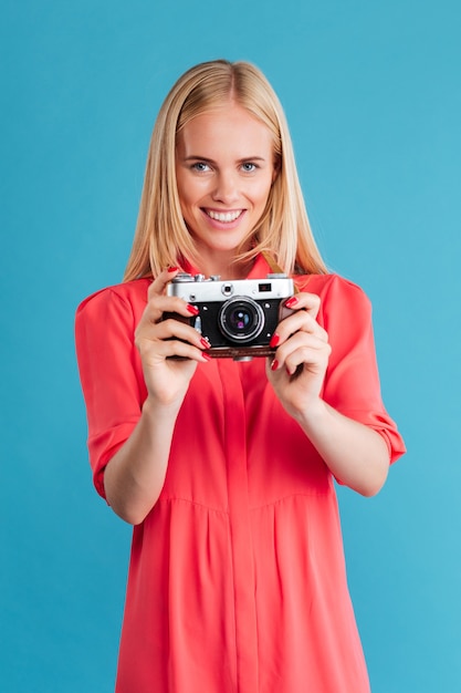 Portrait of a smiling blonde woman holding retro front over blue wall