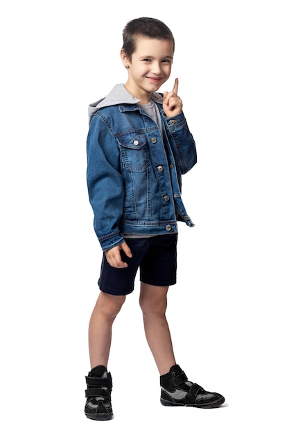 Portrait of smiling boy in denim jacket pointing up and looking at the same place, having fun on white isolated background