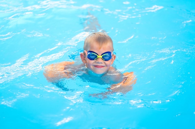 Portrait smiling boy in swimming pool child in swimming glasses and inflatable sleeves Summer travel hotel vacation or classes