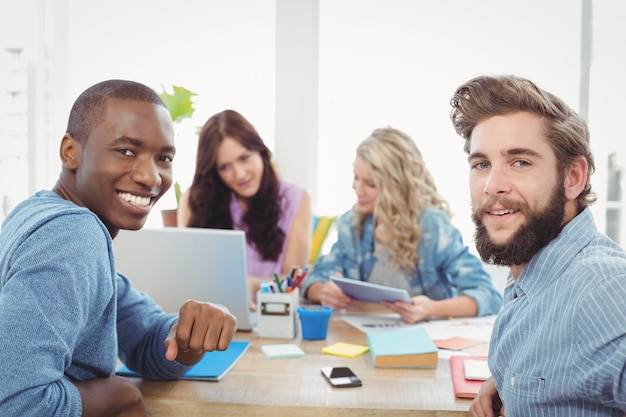 Portrait of smiling business people with women working on background at desk 