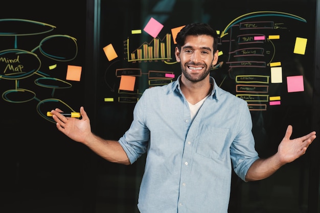 Portrait of smiling businessman standing at glass board with graph Tracery