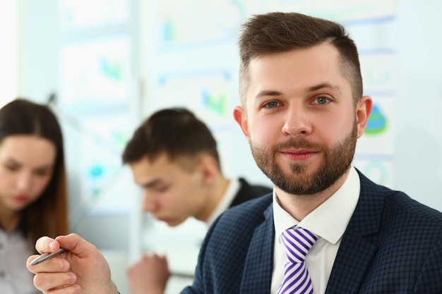 Portrait of smiling businessman with colleagues in a meeting in background in office