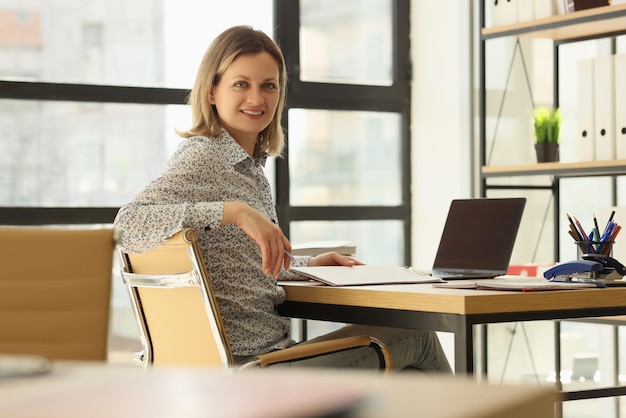 Portrait of smiling businesswoman posing at workplace in office workspace and office interior