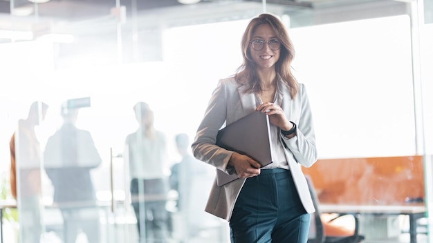 Portrait of smiling businesswoman with laptop with colleague on the background