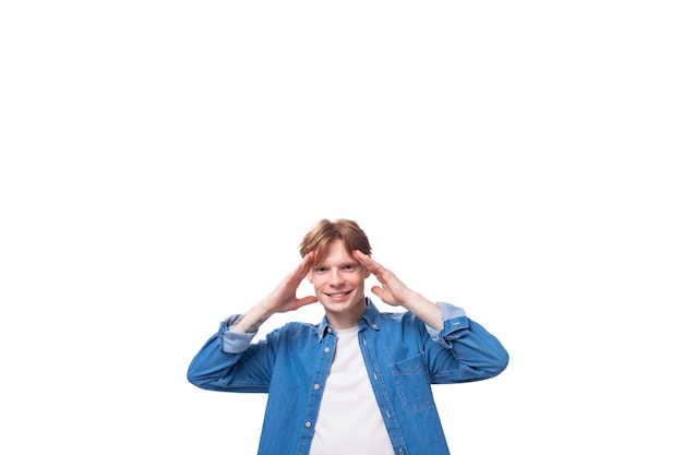 Portrait of a smiling caucasian redhaired guy in a denim blue denim shirt on a studio background