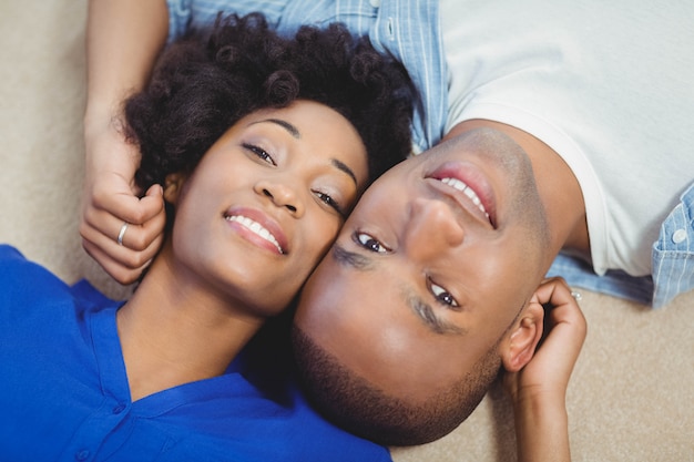 Portrait of smiling couple lying on the floor and looking at the camera