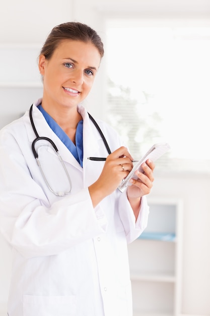 Portrait of a smiling doctor writing something down looking into