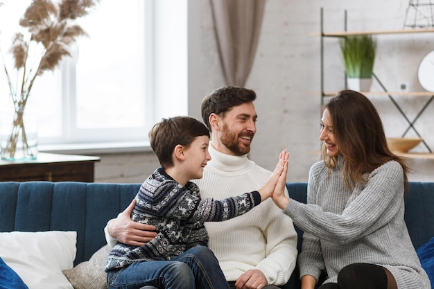 Portrait of smiling father, mother and son. Happy family spending time together at home. Cute boy with mom and dad playing at home. Time to family leisure. Family values.