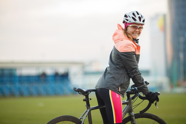 Portrait of smiling female bicyclist in tracksuit outdoors