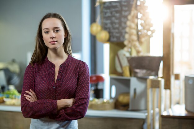 Portrait of smiling female staff standing with arms crossed against counter