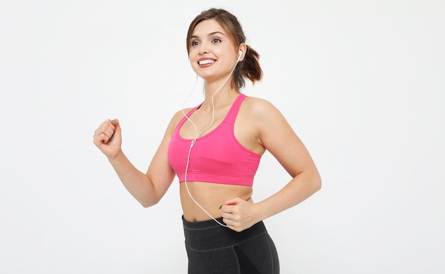 Portrait of a smiling fitness woman in headphones working out isolated over white background