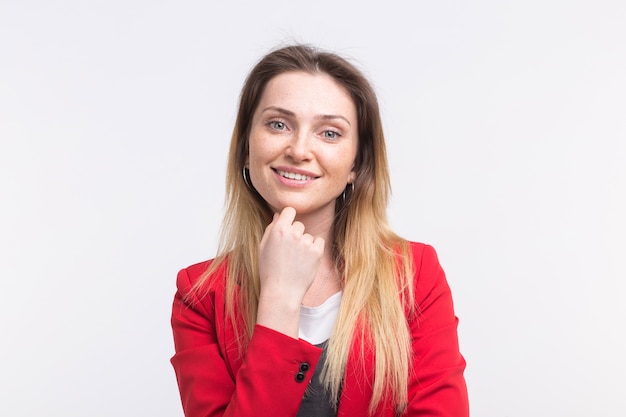 Portrait of smiling freckled beautiful woman with hand on her chin, wearing red