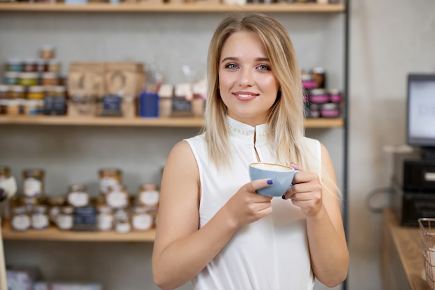 Portrait of smiling girl keeping cup of coffee , looking at camera.