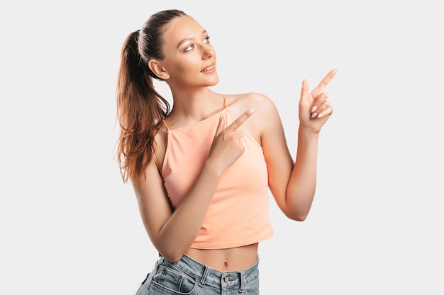 Portrait of a smiling girl pointing finger to the side at on a white isolated background Positive woman points to an idea a place for advertising