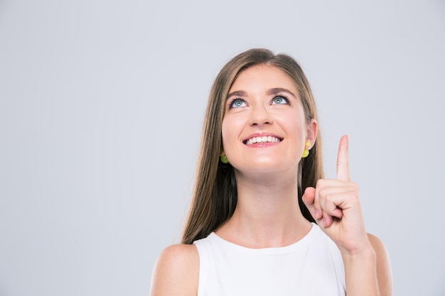 Portrait of a smiling girl pointing finger up at copyspace isolated