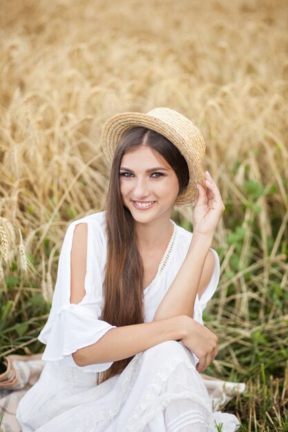 Portrait Smiling girl in straw hat is boatman enjoying nature of wheat field.