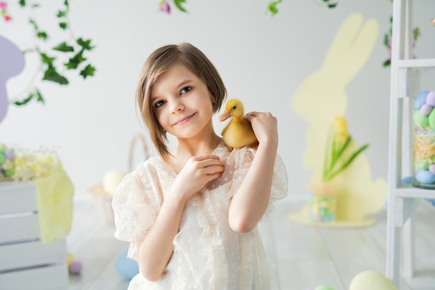 Portrait of smiling girl who holds and communicates with duckling easter decorations happy easter