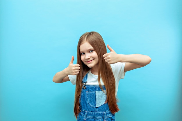 Portrait of a smiling girl with a raised thumb.