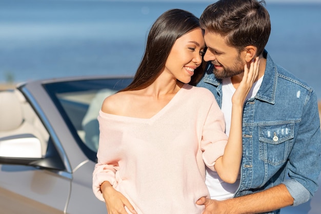 Portrait of smiling girlfriend hugging boyfriend with love outdoors on sunny day