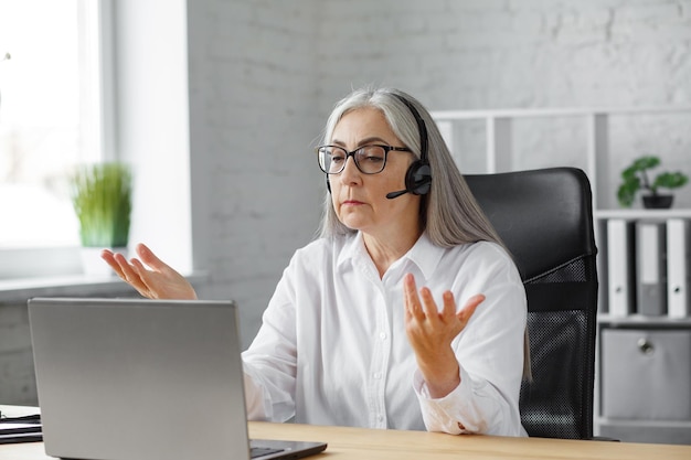 Portrait of smiling greyhaired mature woman using laptop for a online meeting video call video confe