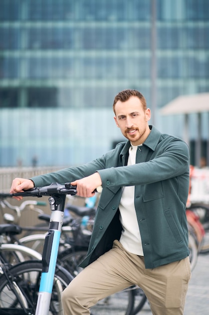 Portrait of smiling handsome man riding electric scooter looking at camera