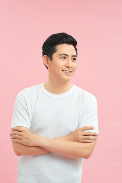 Portrait of smiling handsome man in white t-shirt standing with crossed arms isolated on gray background