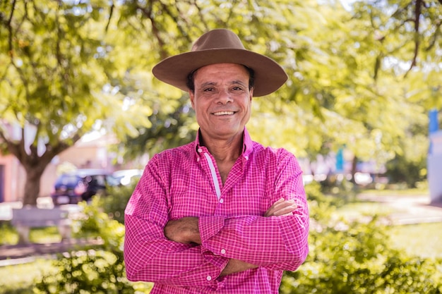 Portrait of smiling handsome older male farmer Elderly farmer with arms crossed smiling looking at camera