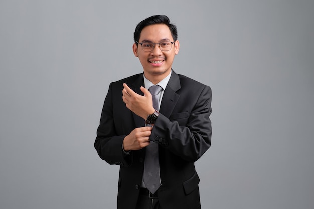 Portrait of smiling handsome young businessman in formal suit feeling relaxed and confident looking at camera isolated on grey background