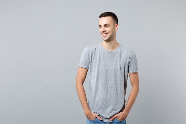 Portrait of smiling handsome young man in casual clothes looking aside, holding pockets in pockets 