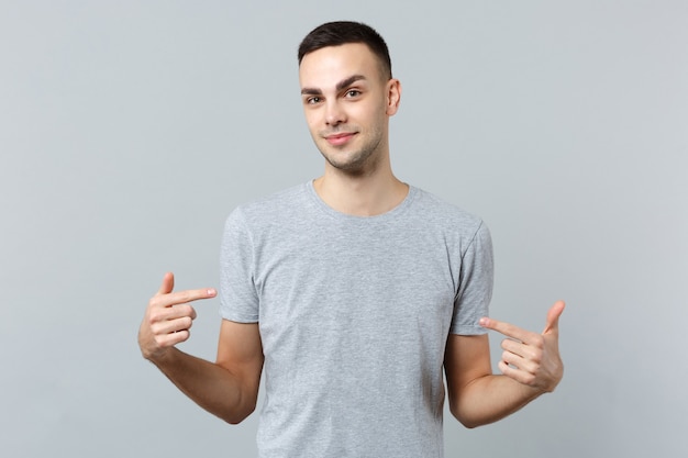 Portrait of smiling handsome young man in casual clothes pointing index fingers on himself 