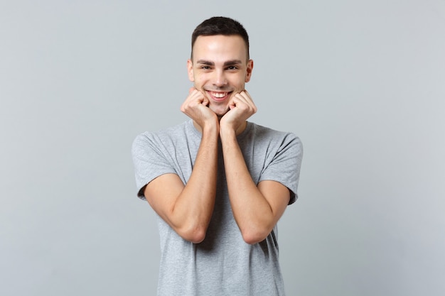 Portrait of smiling handsome young man in casual clothes standing, clenching fists near chin 