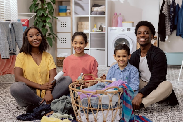 Portrait of a smiling happy african american family sitting on the bathroom floor laundry room