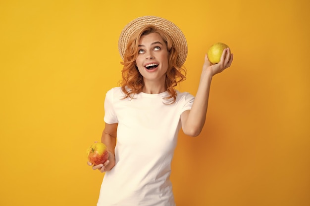 Portrait of a smiling happy girl with apple isolated over yellow background