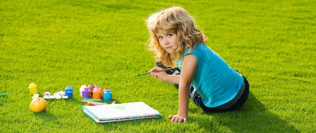 Portrait of smiling happy kid enjoying art and craft drawing in backyard or spring park children dra