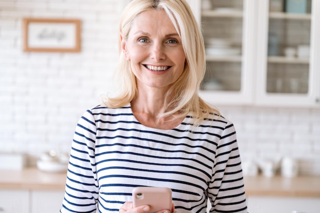 Photo portrait of smiling happy woman holding modern cellphone in hands