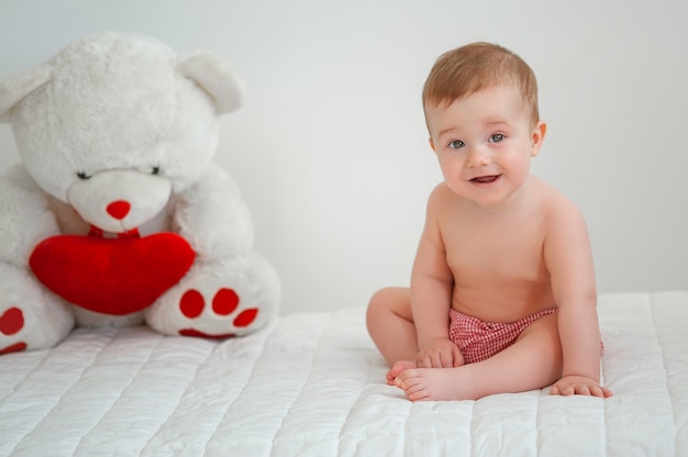 Portrait of a smiling kid with a toy bear on a light background