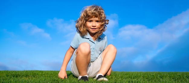 Portrait of a smiling little boy on green grass smiling boy having fun outdoor in spring garden spri