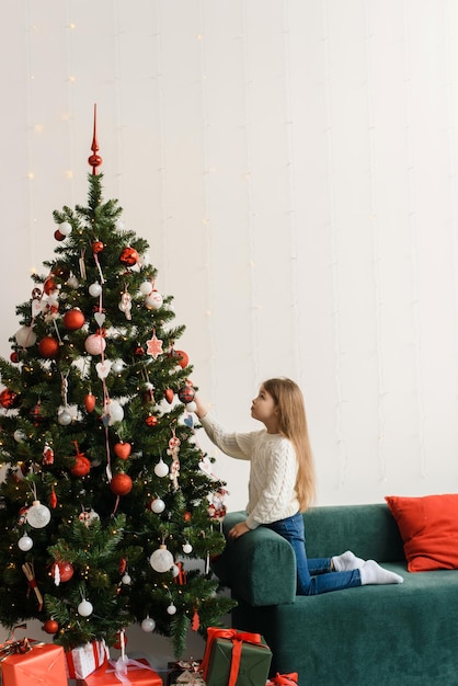 Portrait of a smiling little girl decorating the Christmas tree