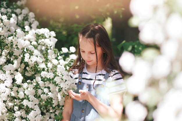 Portrait of a smiling little girl near a flowering tree with white flowers