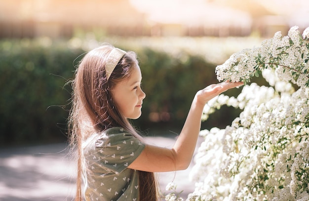 Portrait of a smiling little girl near a flowering tree with white flowers