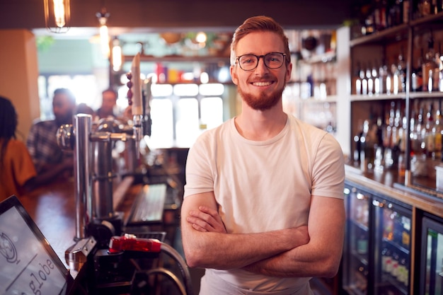 Portrait Of Smiling Male Bar Owner Standing Behind Counter