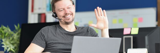 Portrait of smiling male operator who greets customer via video call remote work by operator